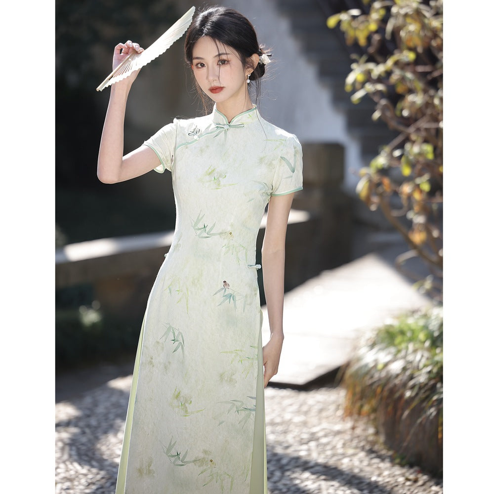 Three-quarter portrait of a woman lifting a fan while modeling the Traditional Velvet Ao Dai Dress in light green velvet fabric. The Vietnamese Ao Dai’s high collar and slim silhouette reflect timeless refinement.
