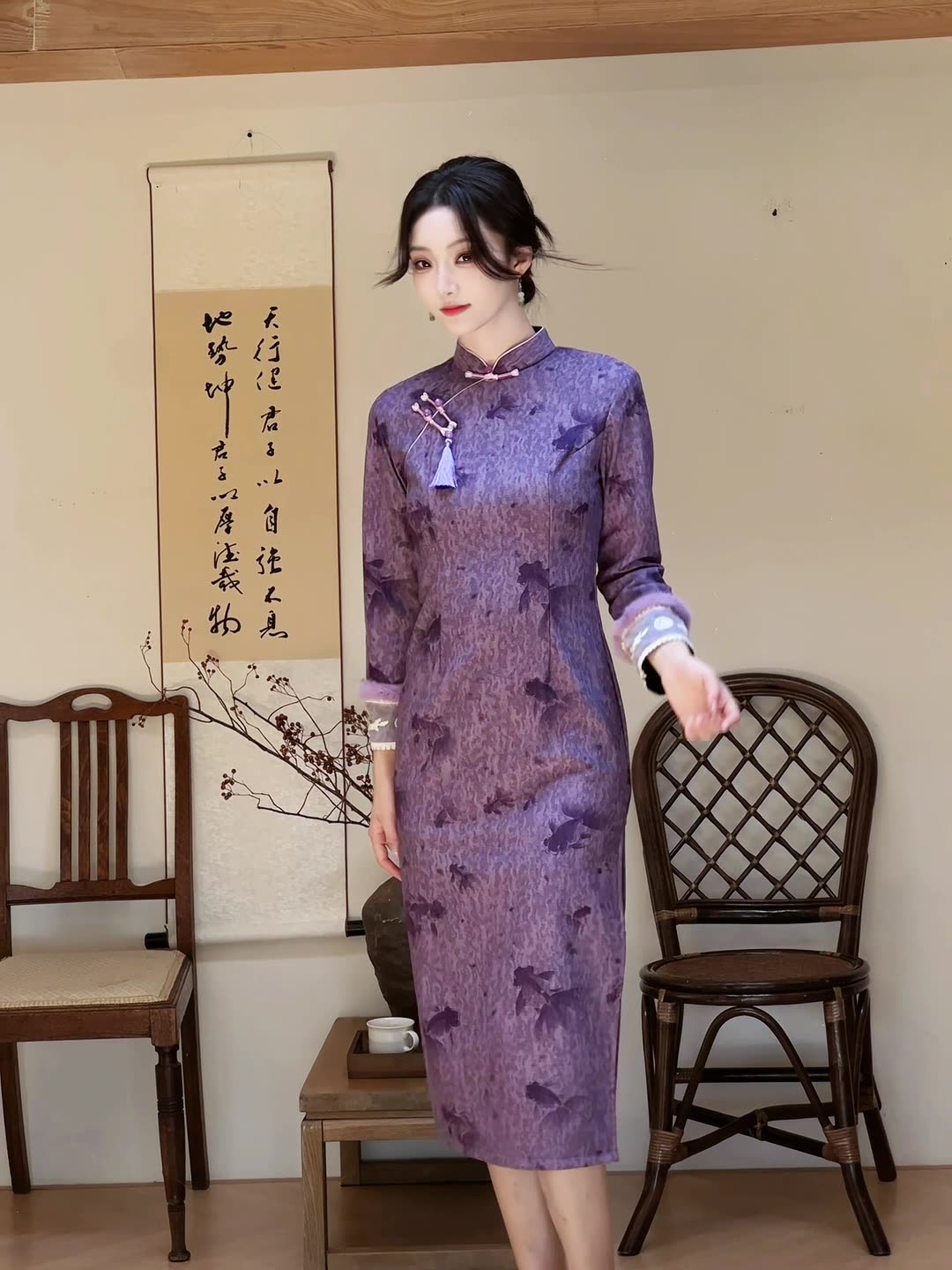 The model stands indoors showcasing the full silhouette of the Twilight Silk Modern Ao Dai Dress, highlighting its tailored fit and flowing movement. The soft violet tone complements classic accessories for a graceful, composed style.