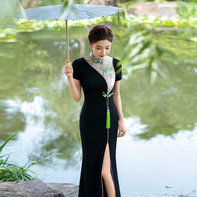 Three-quarter angle shot of a black modern Vietnamese Ao Dai dress with embroidered collar detail, taken outdoors under natural light.