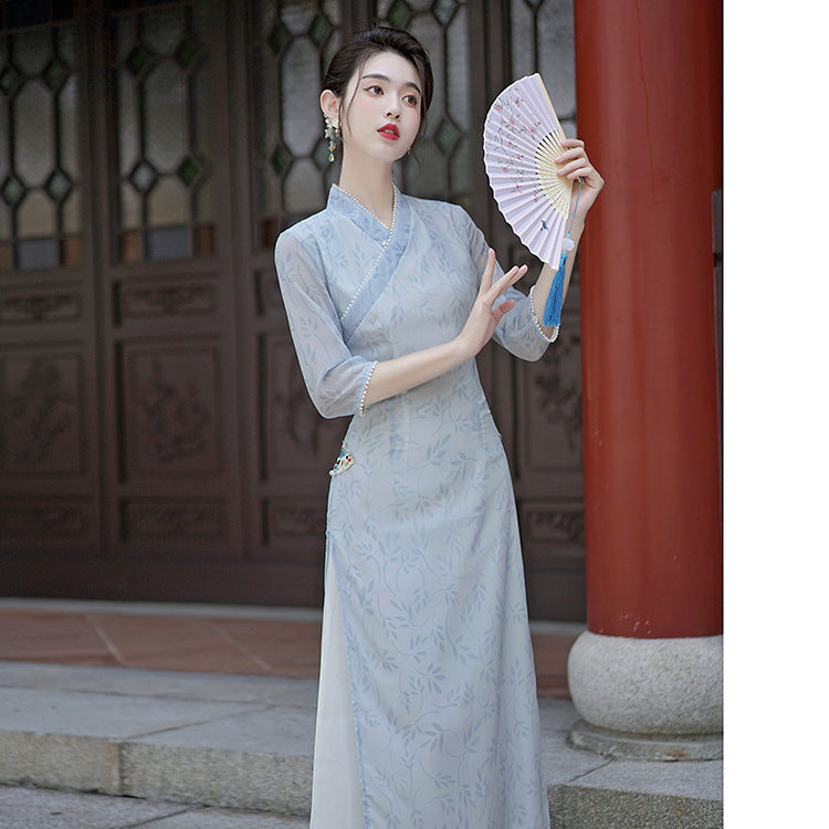 Front view of the ao dai featuring a V-wrap collar, sheer sleeves, and a soft leaf motif throughout the fabric.