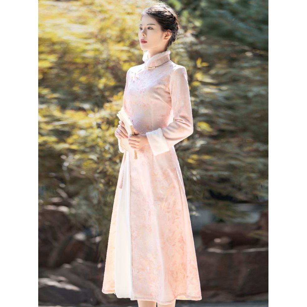 Side profile of the ao dai showing the slim tailored fit, long sleeves, and subtle flower pattern on the pink fabric.